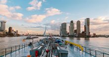 Schip in de Haven van Rotterdam met Erasmusbrug en gebouwen voor een roze lucht