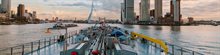 Ship in the Port of Rotterdam with Erasmus Bridge and buildings against a pink sky