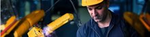 Construction worker working behind a laptop with a robot next to him, wearing work clothes and a helmet
