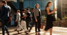 Woman stands still on the street looking up and is passed by other business-attired people