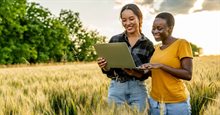 Twee vrouwen bekijken iets op een laptop in een weiland