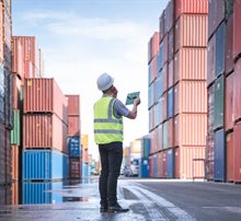 Man staat met tablet tussen containers te werken