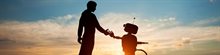 Man and robot stand outside and hold hands