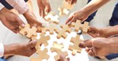 Hands place puzzle pieces and work together