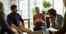 Company meeting of group sitting in a circle on chairs with laptops and tablets in hand