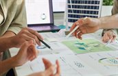 Mensen wijzen met pen naar papieren analyses op tafel